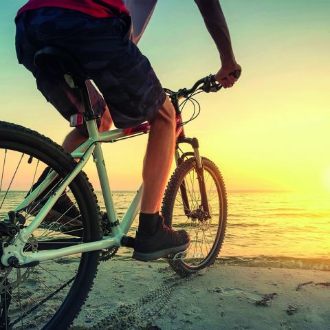 Umgebung Ostseeresidenz Schönberger Strand, Fahrradfahrer am Strand blickt auf die Ostsee bei Sonnenuntergang