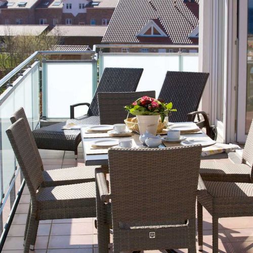 Penthouses Ostseeresidenz Schönberger Strand, Balkon mit zwei Rattanliegen sowie sechs Rattanstühle und Tisch, Tisch ist mit Frühstück eingedeckt